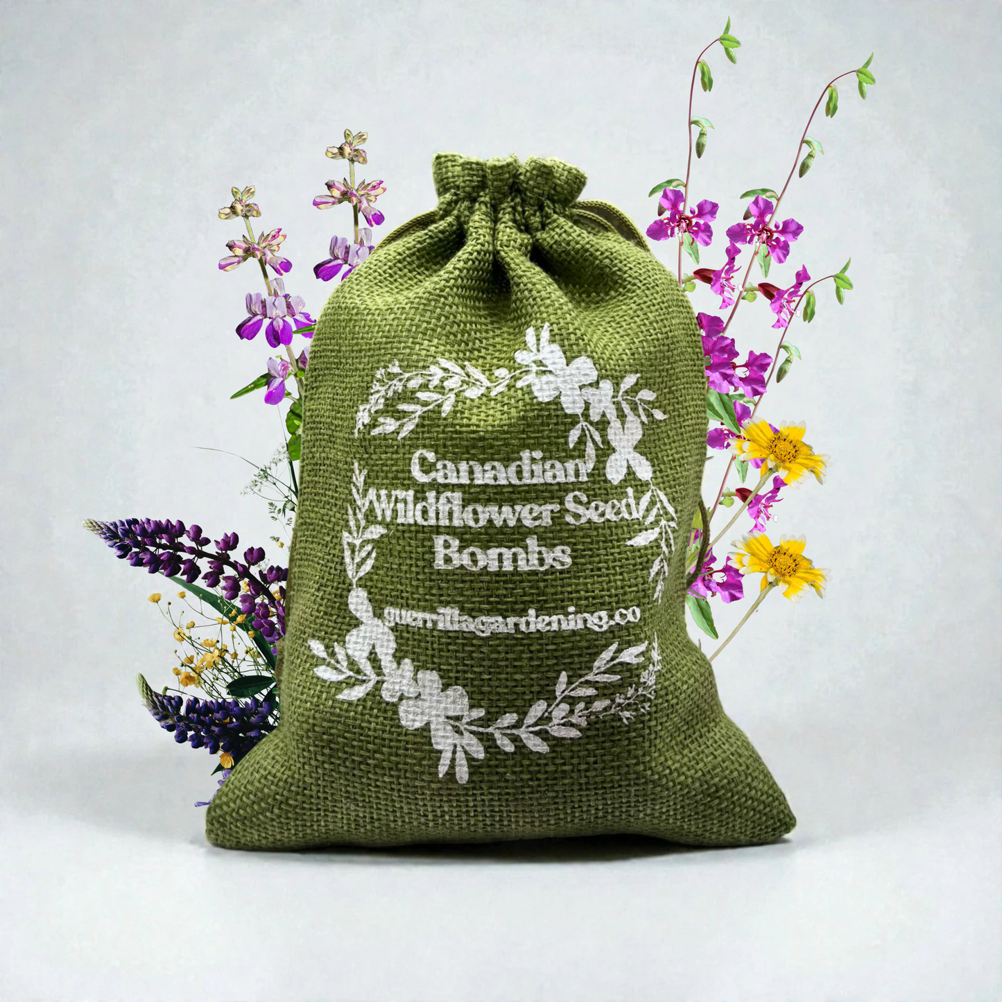 Sac en toile de jute vert contenant des bombes de graines de fleurs sauvages de Colombie-Britannique. Entouré de lupins violets et fleurs roses, mélange spécifique pour l'Ouest canadien.