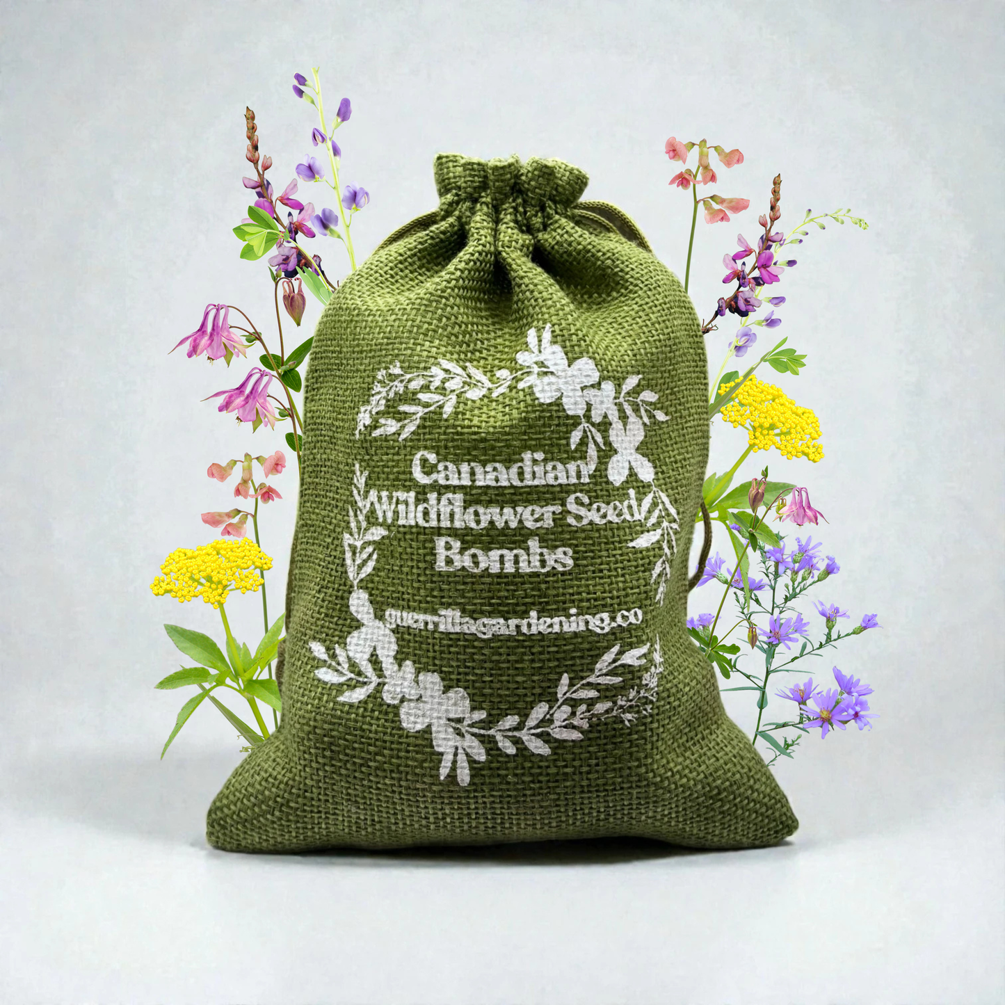 Green burlap bag printed with Canadian Wildflower Seed Bombs, surrounded by purple and yellow wildflowers. Eco-friendly pouch for guerrilla gardening.
